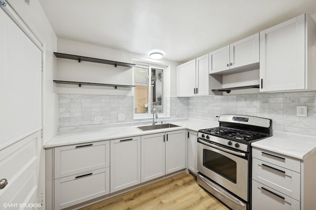 kitchen with stainless steel gas stove, a sink, tasteful backsplash, and open shelves