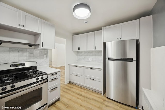 kitchen with light wood finished floors, light countertops, appliances with stainless steel finishes, white cabinetry, and tasteful backsplash