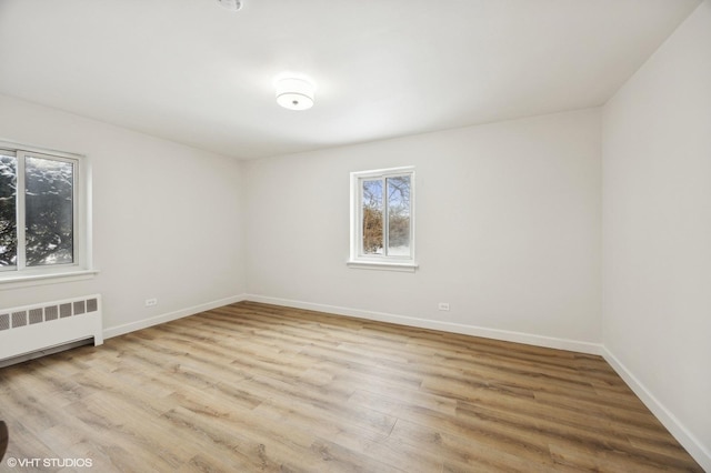 empty room featuring radiator heating unit, wood finished floors, and baseboards