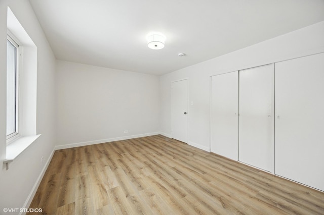 unfurnished bedroom featuring light wood-type flooring, baseboards, and a closet