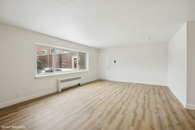 empty room featuring radiator, baseboards, and wood finished floors