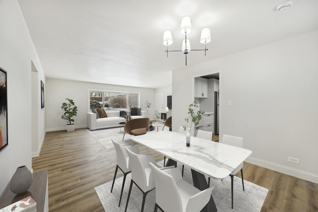 dining room with baseboards, a notable chandelier, and wood finished floors