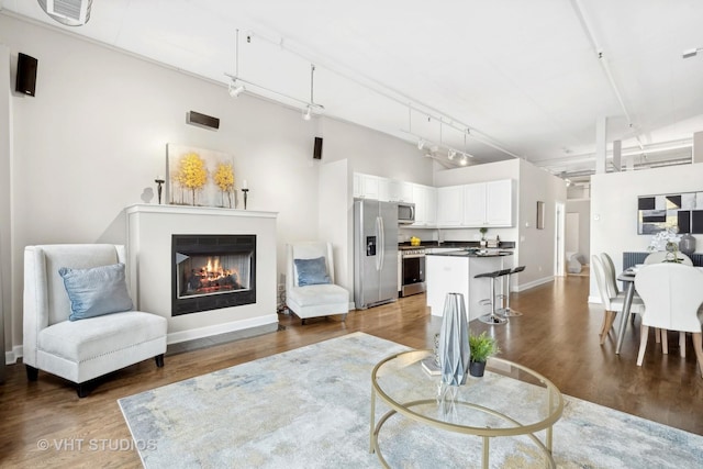 living room featuring a high ceiling, rail lighting, and dark hardwood / wood-style floors