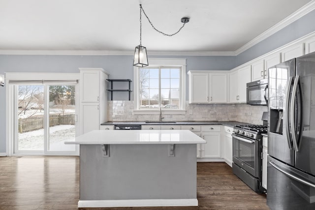 kitchen with a kitchen island, decorative light fixtures, white cabinetry, sink, and stainless steel appliances