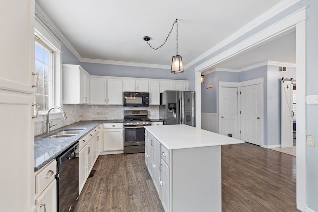 kitchen featuring sink, black appliances, a kitchen island, pendant lighting, and white cabinets