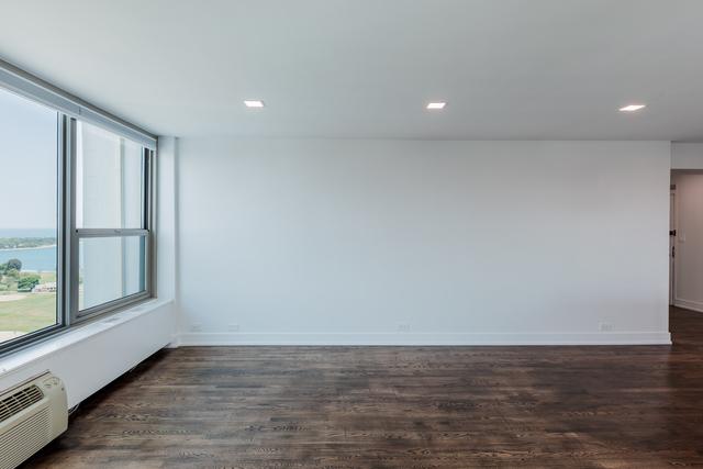 spare room featuring a wall unit AC, a wealth of natural light, a water view, and dark hardwood / wood-style floors