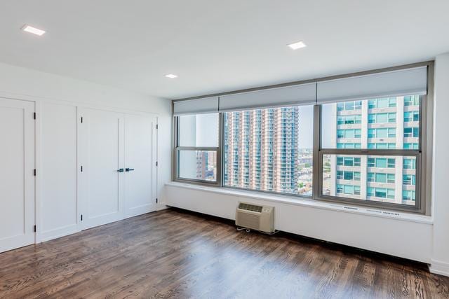 unfurnished room with dark hardwood / wood-style floors, a healthy amount of sunlight, and a wall mounted AC