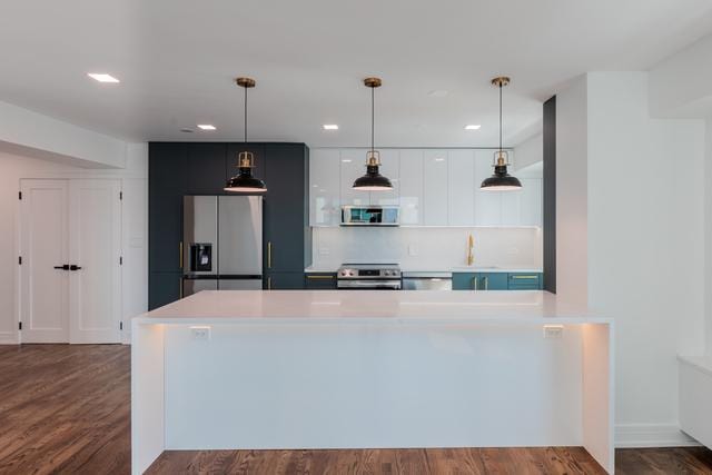 kitchen with appliances with stainless steel finishes, dark hardwood / wood-style flooring, decorative light fixtures, and white cabinetry