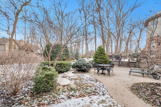 snowy yard featuring a deck and a patio area