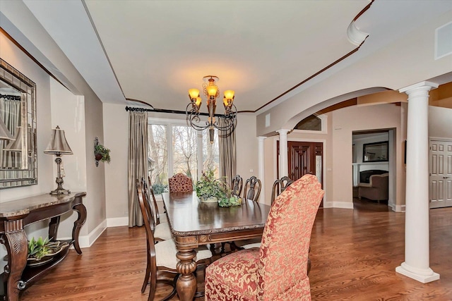 dining room featuring arched walkways, wood finished floors, decorative columns, and a chandelier