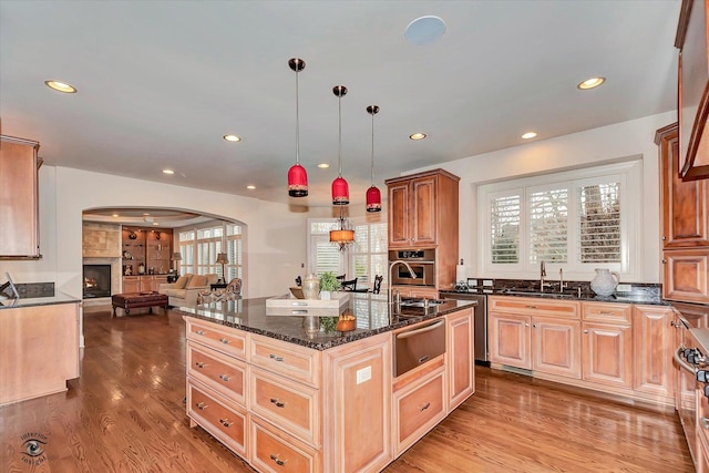 kitchen featuring open floor plan, a center island, hanging light fixtures, stainless steel oven, and a warming drawer