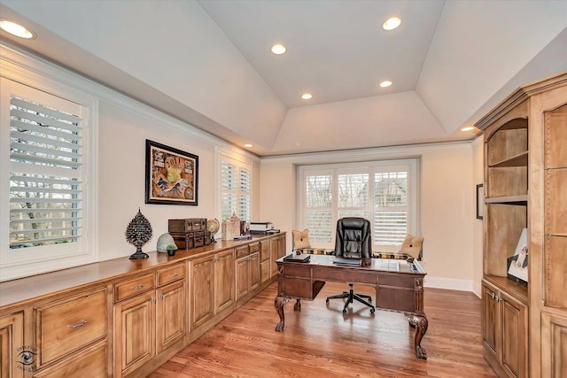 office space featuring baseboards, a raised ceiling, ornamental molding, light wood-style floors, and recessed lighting