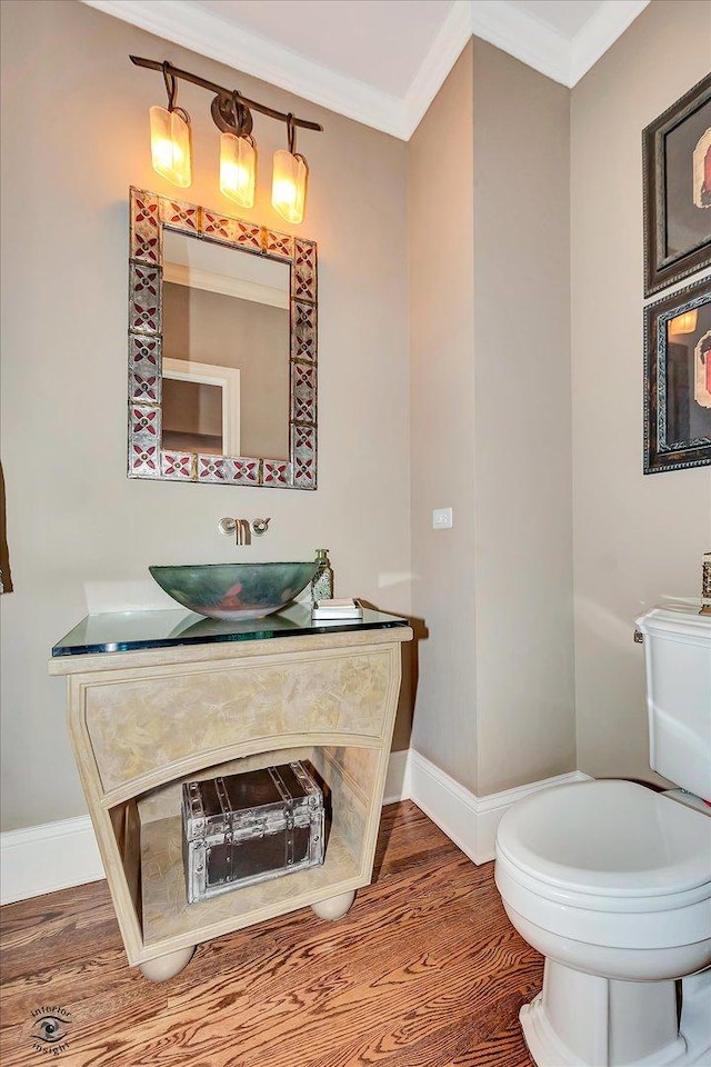 bathroom featuring toilet, baseboards, ornamental molding, and wood finished floors