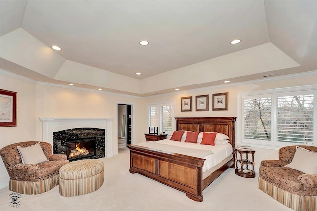 bedroom with a tray ceiling, light colored carpet, a high end fireplace, and crown molding