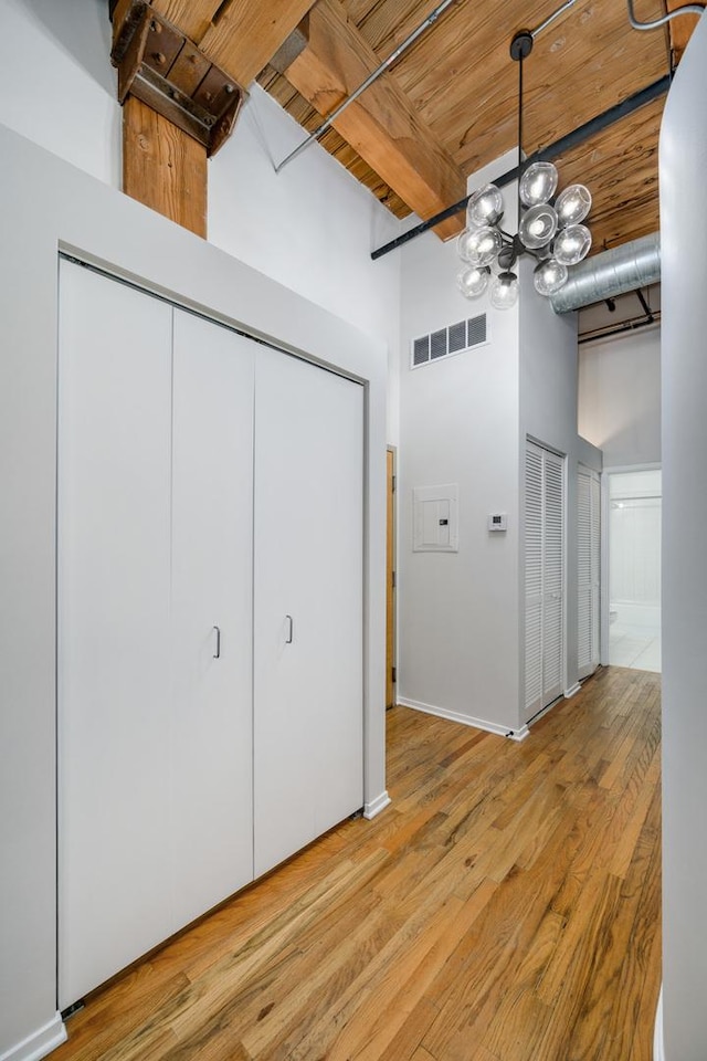 interior space featuring light hardwood / wood-style floors, a towering ceiling, beamed ceiling, a chandelier, and wooden ceiling