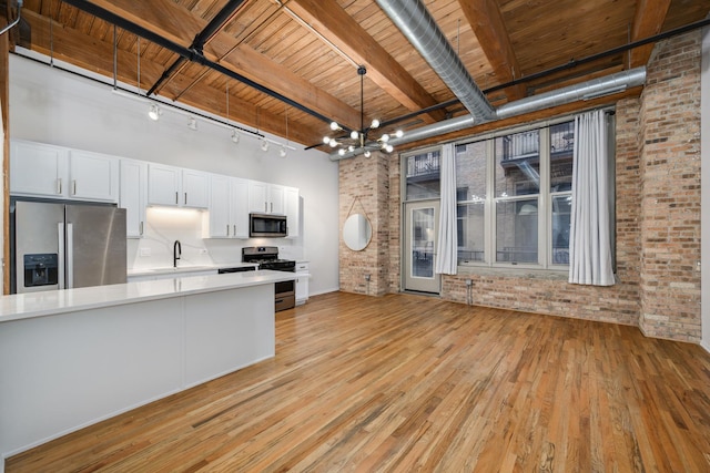 kitchen featuring sink, brick wall, white cabinets, and stainless steel appliances