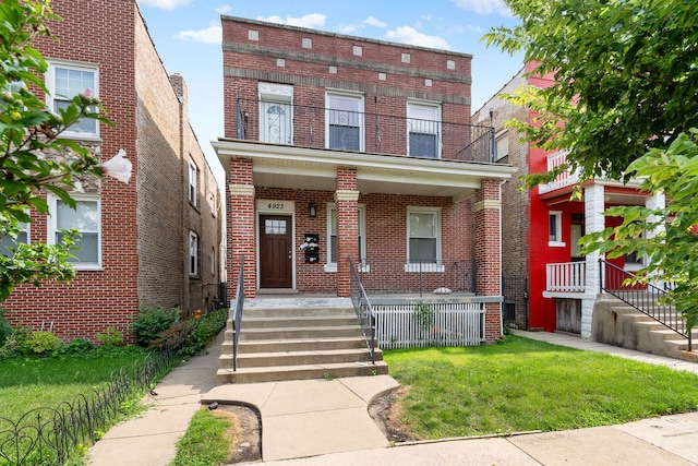 view of front of house featuring covered porch, a balcony, and a front yard