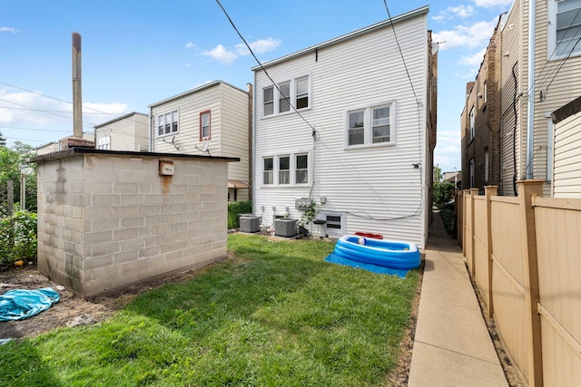 rear view of house with a lawn and central AC unit