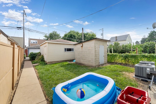 view of pool with a yard, central AC, and a storage unit