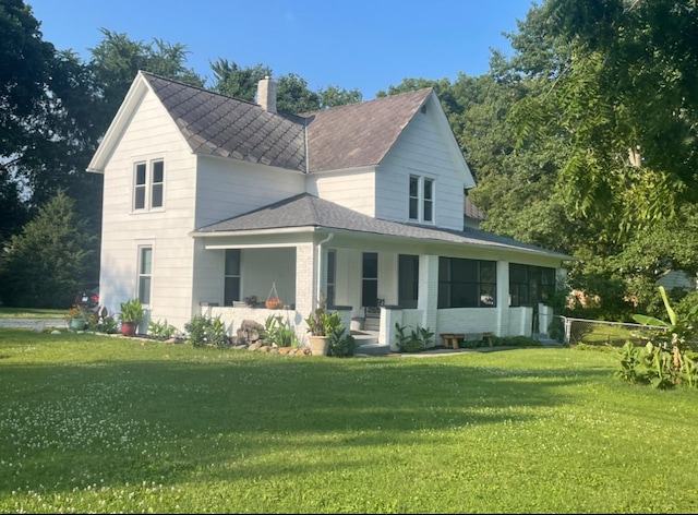 view of front of property featuring a chimney, a shingled roof, covered porch, fence, and a front lawn