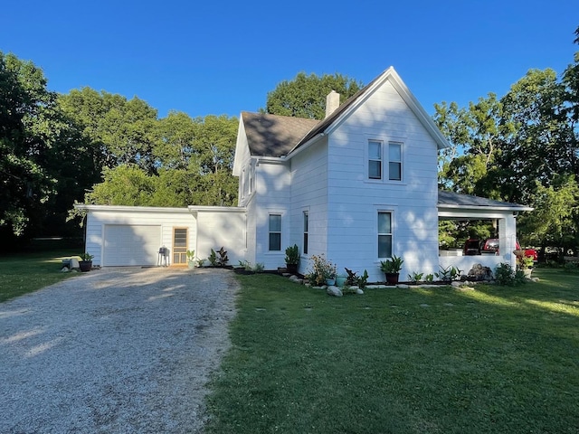 view of front facade featuring a garage, driveway, a chimney, and a front yard