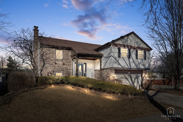 tri-level home featuring brick siding, a chimney, and an attached garage