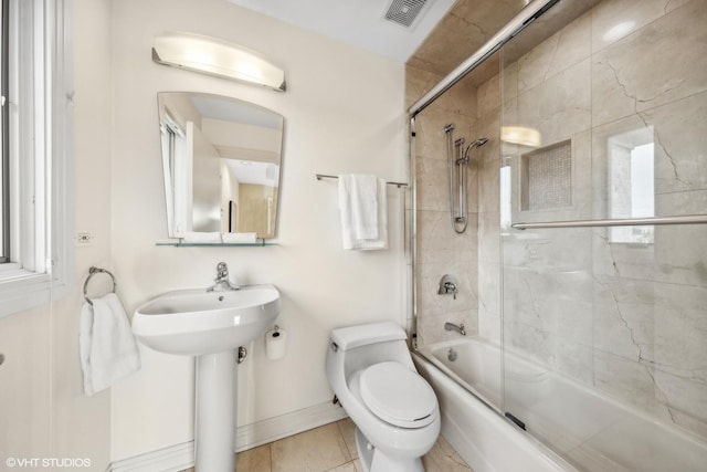 bathroom with tile patterned flooring, toilet, and bath / shower combo with glass door