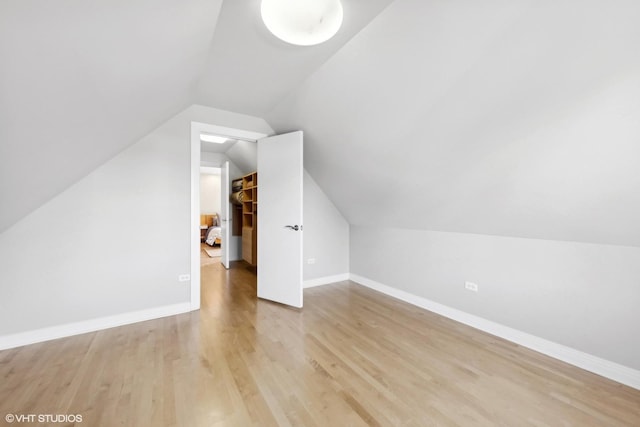 additional living space with light hardwood / wood-style floors and vaulted ceiling