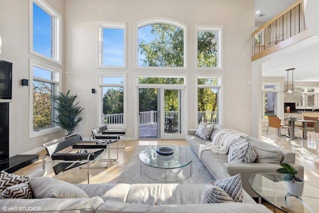 living room with a healthy amount of sunlight, a towering ceiling, and french doors