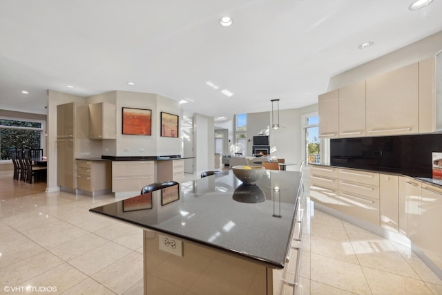 kitchen featuring tasteful backsplash, a large island, light tile patterned floors, and decorative light fixtures