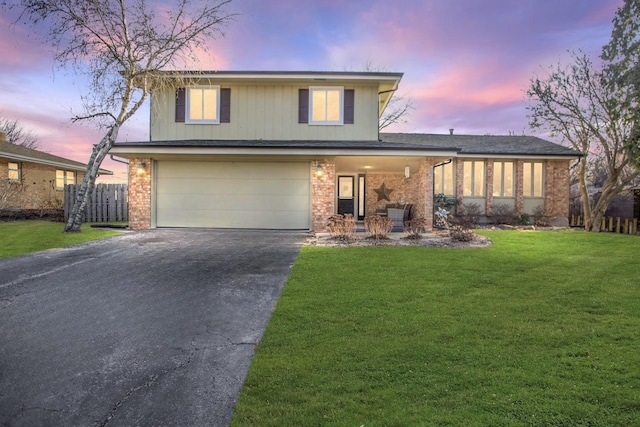 view of front of house with aphalt driveway, brick siding, a yard, an attached garage, and fence