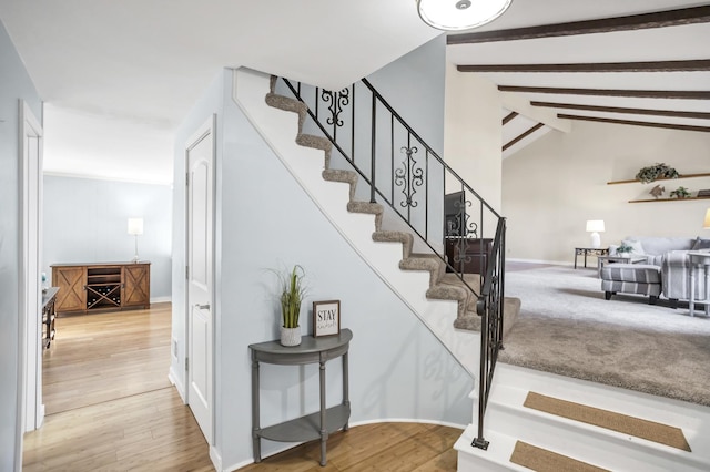 staircase with vaulted ceiling with beams, baseboards, and wood finished floors