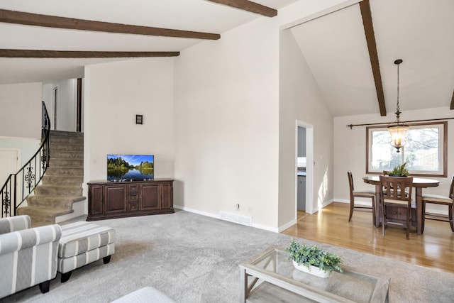 living area with baseboards, visible vents, light colored carpet, stairs, and beam ceiling