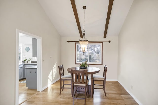 dining area featuring light wood-style flooring, lofted ceiling with beams, and baseboards