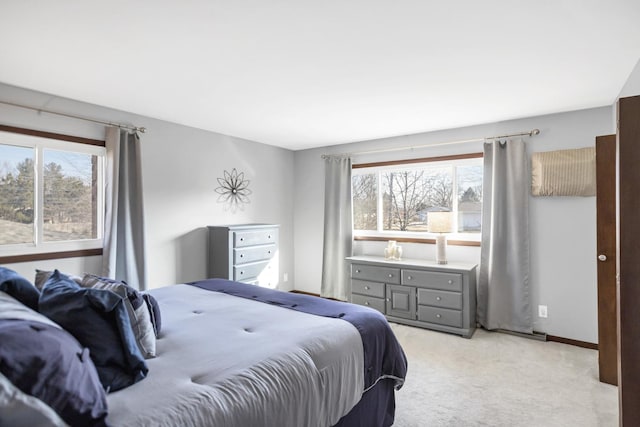 bedroom with multiple windows, baseboards, and light colored carpet