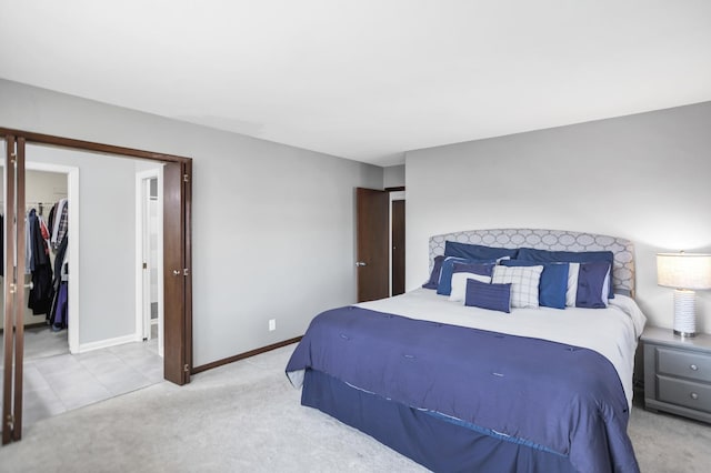 bedroom with light carpet, a spacious closet, baseboards, and a closet