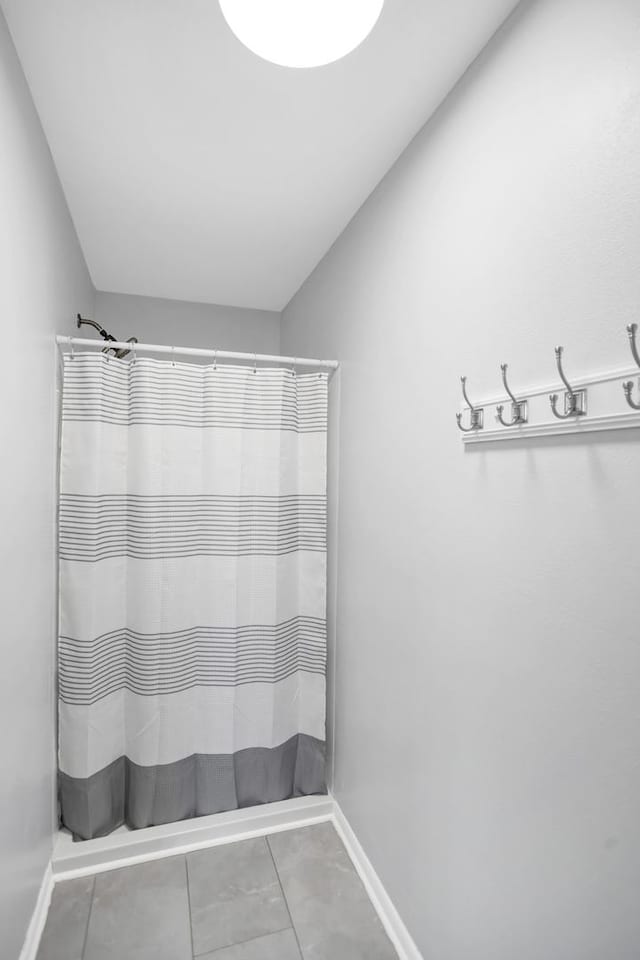 full bath featuring a shower with curtain, baseboards, and tile patterned floors