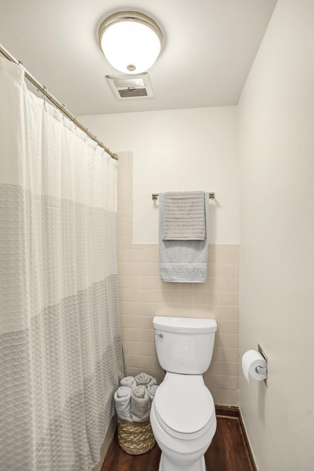 full bath with visible vents, wainscoting, toilet, wood finished floors, and tile walls