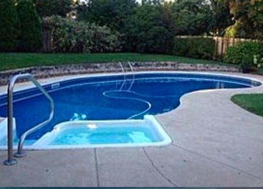 view of swimming pool with a jacuzzi and a fenced in pool