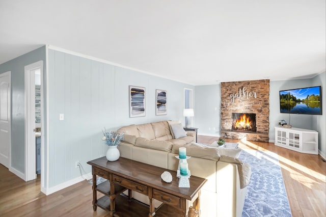 living area featuring a fireplace, baseboards, and wood finished floors