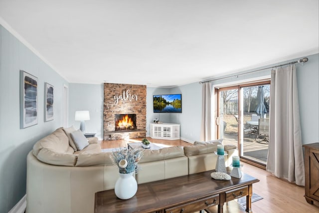 living area featuring a large fireplace, light wood-type flooring, and baseboards