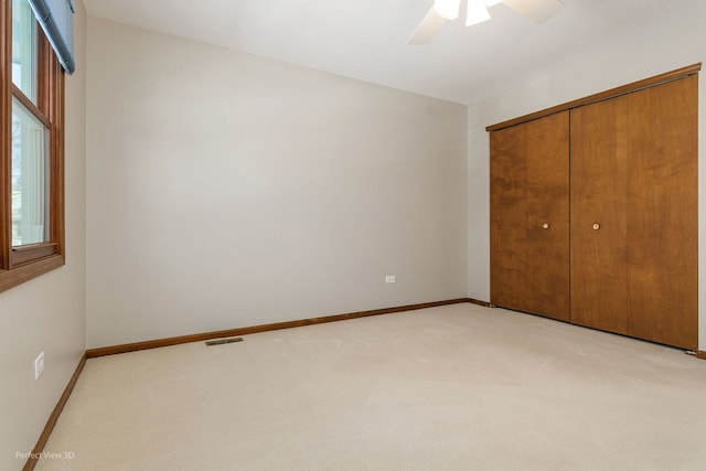 unfurnished bedroom with light colored carpet, a closet, and ceiling fan