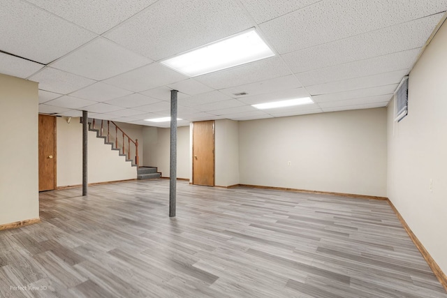 basement with a drop ceiling and light hardwood / wood-style floors