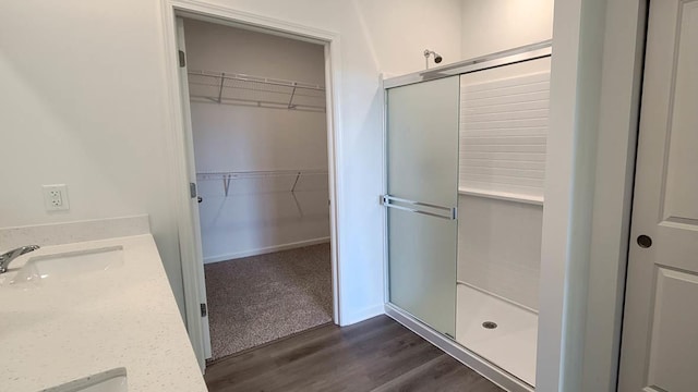 bathroom with walk in shower, vanity, and hardwood / wood-style flooring