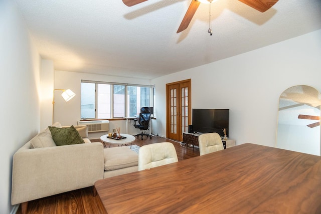 living room featuring french doors, a textured ceiling, ceiling fan, hardwood / wood-style flooring, and an AC wall unit