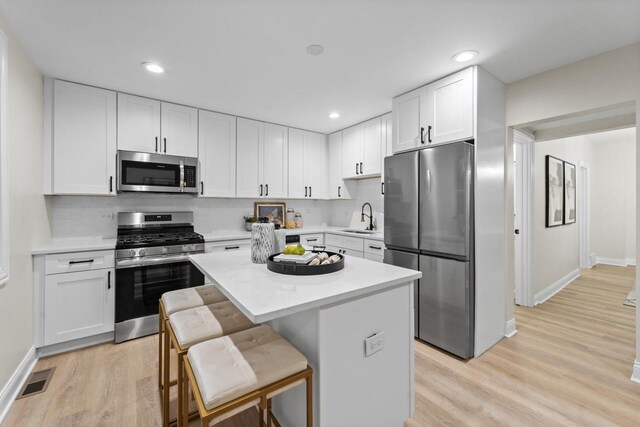 kitchen with white cabinetry, sink, a center island, a breakfast bar area, and appliances with stainless steel finishes