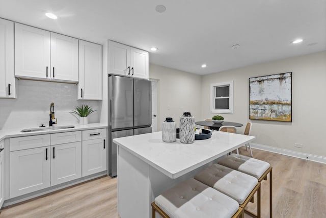 kitchen with light wood-type flooring, white cabinetry, and sink