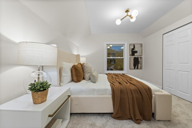 bedroom featuring light carpet, vaulted ceiling, and a notable chandelier