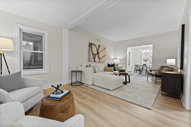 living room with light wood-type flooring and an inviting chandelier