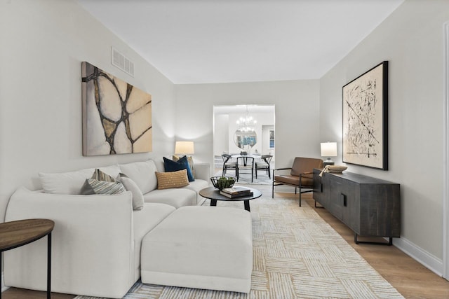 living room with light wood-type flooring and an inviting chandelier